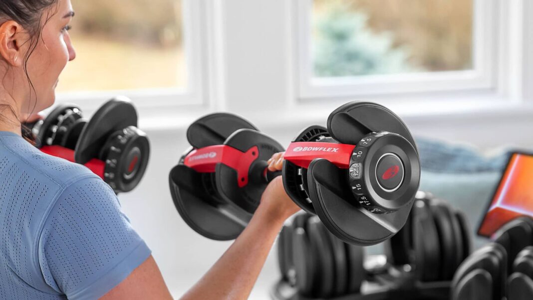 woman lifting bowflex weights in home gym
