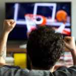 man watching basketball on his new TV he bought on Black Friday at a major discount! Find more TV deals this Black Friday on Slickdeals!